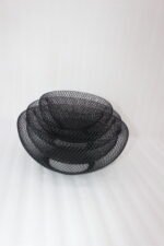 Set of three round black wire mesh decorative metal baskets displayed on a wooden kitchen countertop.