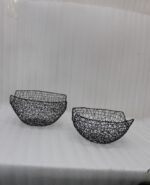 Set of two modern black wire mesh decorative baskets sitting on a wooden kitchen island countertop.