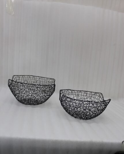 Set of two modern black wire mesh decorative baskets sitting on a wooden kitchen island countertop.