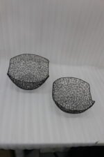 Set of two modern black wire mesh decorative baskets sitting on a wooden kitchen island countertop.