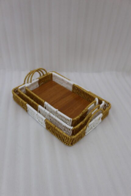 Set of three rectangular handwoven rattan serving trays with wooden bases and handles on a wooden table.