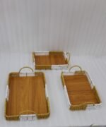 Set of three rectangular handwoven rattan serving trays with wooden bases and handles on a wooden table.