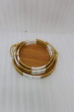 Three-piece round handwoven rattan serving tray set with white and tan woven edges and wooden bases on a light wood table.