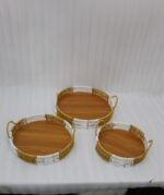 Three-piece round handwoven rattan serving tray set with white and tan woven edges and wooden bases on a light wood table.