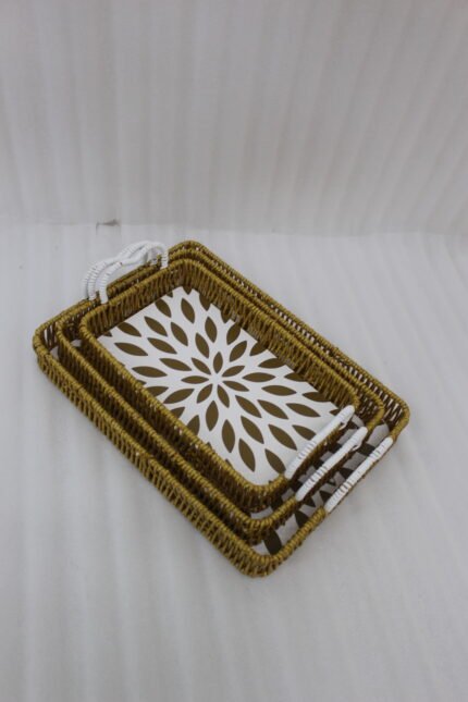 Three rectangular woven rattan serving trays with white decorative floral bottoms and side handles on a wooden table.