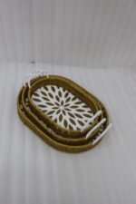 Set of 3 oval woven rattan serving trays with white handles and a modern geometric floral pattern base resting on a wooden table.