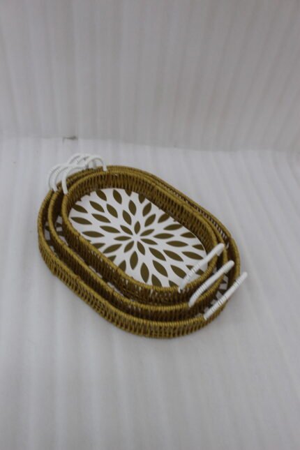 Set of 3 oval woven rattan serving trays with white handles and a modern geometric floral pattern base resting on a wooden table.