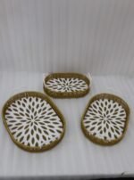Set of 3 oval woven rattan serving trays with white handles and a modern geometric floral pattern base resting on a wooden table.