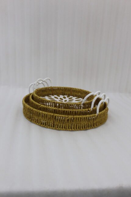 Set of 3 round handwoven rattan serving trays with white base patterns and handles resting on a wooden table