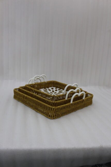3-piece handwoven rattan serving tray set with white floral printed base and white handles on a wooden table.