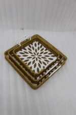 3-piece handwoven rattan serving tray set with white floral printed base and white handles on a wooden table.