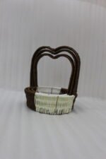Nested set of three brown and cream woven rattan baskets with heart-shaped arch handles on a wooden table.