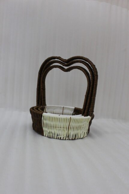 Nested set of three brown and cream woven rattan baskets with heart-shaped arch handles on a wooden table.
