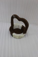 Nested set of three brown and cream woven rattan baskets with heart-shaped arch handles on a wooden table.