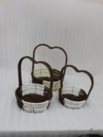 Nested set of three brown and cream woven rattan baskets with heart-shaped arch handles on a wooden table.