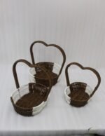 Nested set of three brown and white handwoven rattan trays featuring tall heart-shaped handles on a wooden table