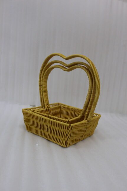 Set of 3 yellow woven rattan nesting trays with high arched handles stacked on a wooden coffee table.