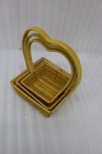Set of 3 yellow woven rattan nesting trays with high arched handles stacked on a wooden coffee table.