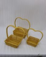 Set of 3 yellow woven rattan nesting trays with high arched handles stacked on a wooden coffee table.