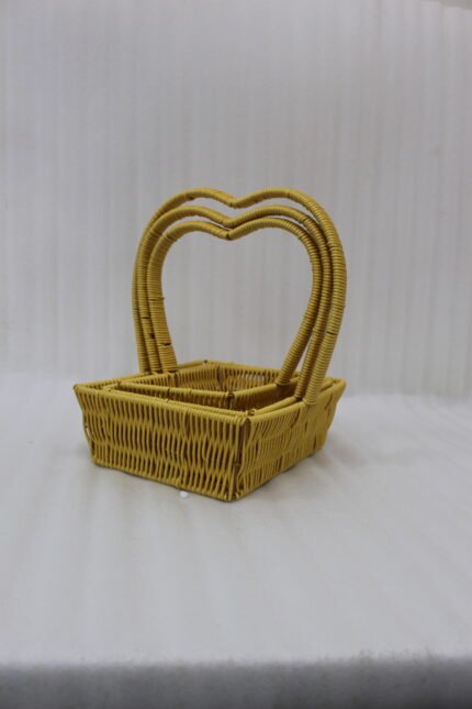 Three yellow handwoven rattan baskets nested together featuring prominent heart-shaped top handles on a wooden table.