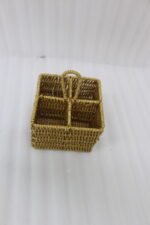 Two handwoven rattan spoon holders with four divided compartments and loop handles sitting on a marble table.