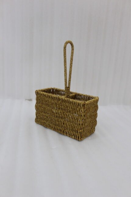 Handwoven rattan spoon holder basket with center handle and two compartments on a wooden table.