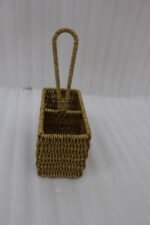 Handwoven rattan spoon holder basket with center handle and two compartments on a wooden table.