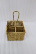 Two handwoven rattan spoon holders with four divided compartments and loop handles sitting on a marble table.