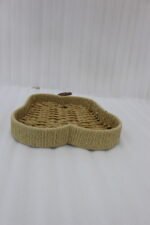 Handwoven light brown rattan fruit dish shaped like an apple resting on a rustic wooden table