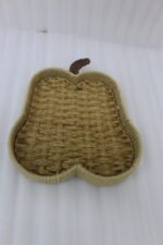 Handwoven light brown rattan fruit dish shaped like an apple resting on a rustic wooden table