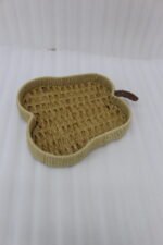Handwoven light brown rattan fruit dish shaped like an apple resting on a rustic wooden table