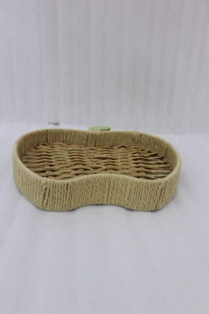Handwoven apple-shaped natural rattan fruit dish sitting on a wooden coffee table in a modern living room setting.