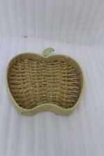 Handwoven apple-shaped natural rattan fruit dish sitting on a wooden coffee table in a modern living room setting.