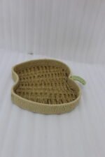 Handwoven apple-shaped natural rattan fruit dish sitting on a wooden coffee table in a modern living room setting.