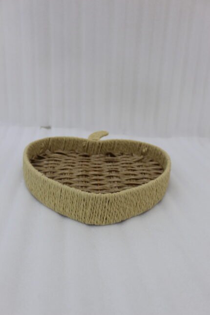 Apple-shaped handwoven rattan fruit tray sitting on a light wooden table