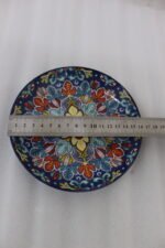 Decorative ceramic bowls with traditional Marrakech hand-painted designs on a rustic wooden dining table.