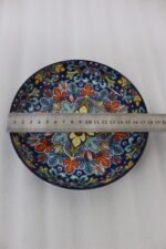 Decorative ceramic bowls with traditional Marrakech hand-painted designs on a rustic wooden dining table.
