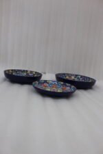 Decorative ceramic bowls with traditional Marrakech hand-painted designs on a rustic wooden dining table.