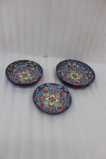 Decorative ceramic bowls with traditional Marrakech hand-painted designs on a rustic wooden dining table.