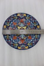 Two vibrant blue, yellow, and red decorative Marrakech ceramic plates displaying intricate mosaic patterns on a white marble surface in 8-inch and 10-inch sizes.