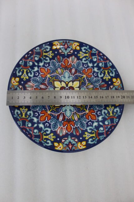 Two vibrant blue, yellow, and red decorative Marrakech ceramic plates displaying intricate mosaic patterns on a white marble surface in 8-inch and 10-inch sizes.