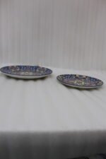 Two vibrant blue, yellow, and red decorative Marrakech ceramic plates displaying intricate mosaic patterns on a white marble surface in 8-inch and 10-inch sizes.