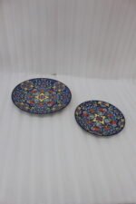 Two vibrant blue, yellow, and red decorative Marrakech ceramic plates displaying intricate mosaic patterns on a white marble surface in 8-inch and 10-inch sizes.