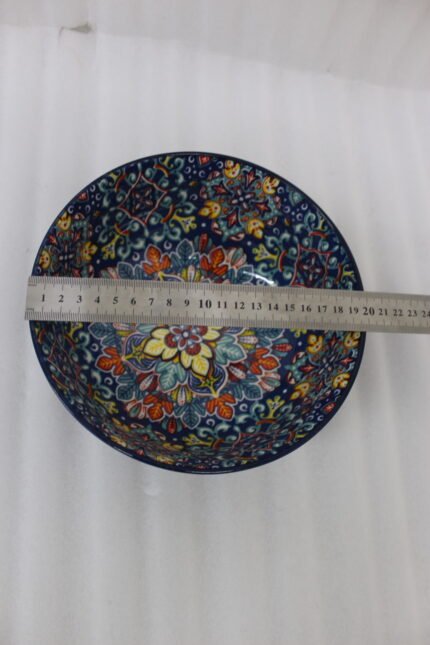 Set of three hand-painted decorative Marrakech ceramic bowls with colorful bohemian patterns and navy blue exteriors on a slate table.