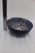 Set of three hand-painted decorative Marrakech ceramic bowls with colorful bohemian patterns and navy blue exteriors on a slate table.
