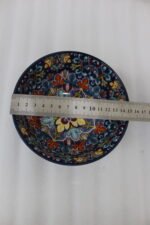 Set of three hand-painted decorative Marrakech ceramic bowls with colorful bohemian patterns and navy blue exteriors on a slate table.