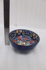 Set of three hand-painted decorative Marrakech ceramic bowls with colorful bohemian patterns and navy blue exteriors on a slate table.