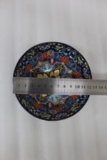 Set of three hand-painted decorative Marrakech ceramic bowls with colorful bohemian patterns and navy blue exteriors on a slate table.