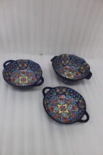 Three hand-painted decorative Marrakech ceramic bowls with intricate bohemian patterns and handles arranged on a dining table runner.