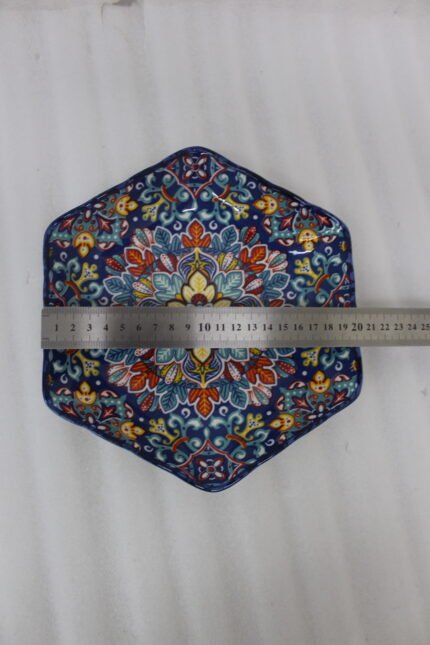 Decorative Marrakesh ceramic serving dish with colorful Moroccan mosaic pattern resting on a wooden dining table.